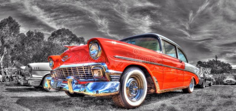 Classic American built orange and white 1950s Chevy sedan on display at car and bike show in Melbourne, Australia. On a black and white background of original photo. Classic American built orange and white 1950s Chevy sedan on display at car and bike show in Melbourne, Australia. On a black and white background of original photo