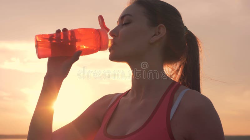 Η καλή νέα κυρία πίνει από ένα πορτοκαλί μπουκάλι υπαίθρια φιλμ μικρού μήκους