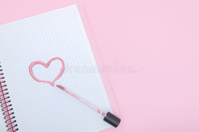 Η καρδιά είναι χρωματισμένη με ένα κραγιόν σε ένα σημειωματάριο σε ένα ρόδινο υπόβαθρο Έννοια αγάπης και ομορφιάς στοκ εικόνα Η καρδιά είναι χρωματισμένη με ένα κραγιόν σε ένα σημειωματάριο σε ένα ρόδινο υπόβαθρο Έννοια αγάπης και ομορφιάς στοκ εικόνα