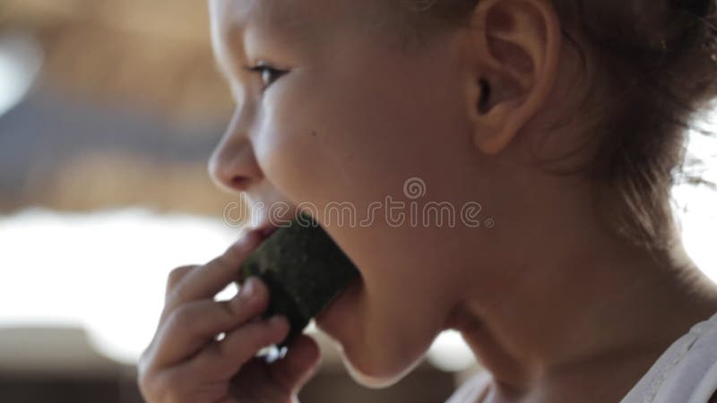 Η κινηματογράφηση σε πρώτο πλάνο λίγης χαριτωμένης συνεδρίασης κοριτσάκι στην ταλάντευση και τρώει το κόκκινο καρπούζι