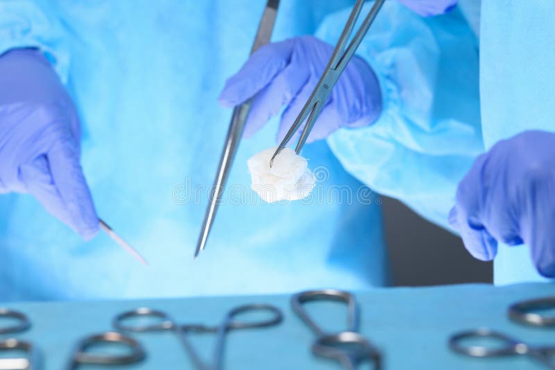 Η κινηματογράφηση σε πρώτο πλάνο των χεριών χειρούργων στην εργασία στο λειτουργούν θέατρο τόνισε στο μπλε στοκ φωτογραφία Η κινηματογράφηση σε πρώτο πλάνο των χεριών χειρούργων στην εργασία στο λειτουργούν θέατρο τόνισε στο μπλε στοκ φωτογραφία