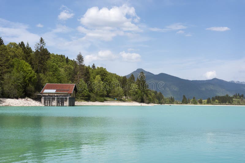 Η λίμνη Walchensee με το boathouse και το βουνό κυμαίνονται - χαρακτηριστική αλπική λίμνη στις βαυαρικές Άλπεις με απίστευτοι σαφ στοκ εικόνες Η λίμνη Walchensee με το boathouse και το βουνό κυμαίνονται - χαρακτηριστική αλπική λίμνη στις βαυαρικές Άλπεις με απίστευτοι σαφ στοκ εικόνες