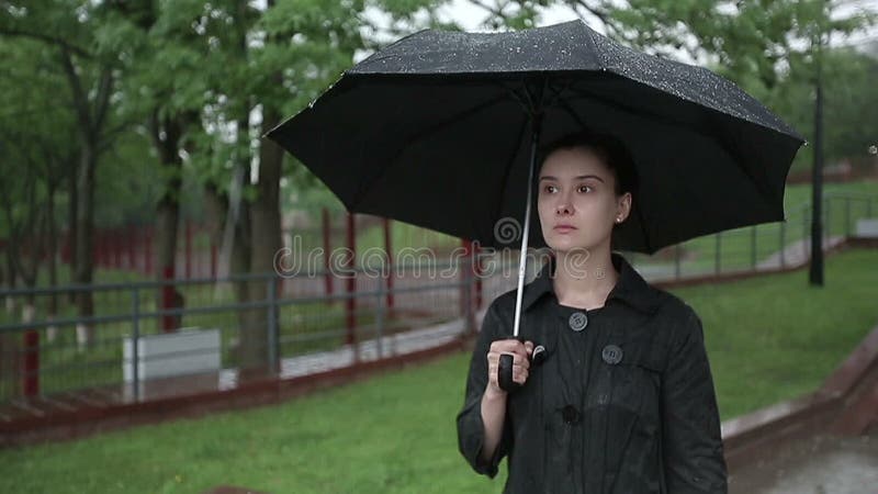 Η μόνη λυπημένη γυναίκα περπατά κάτω από την οδό στη δυνατή βροχή κίνηση αργή