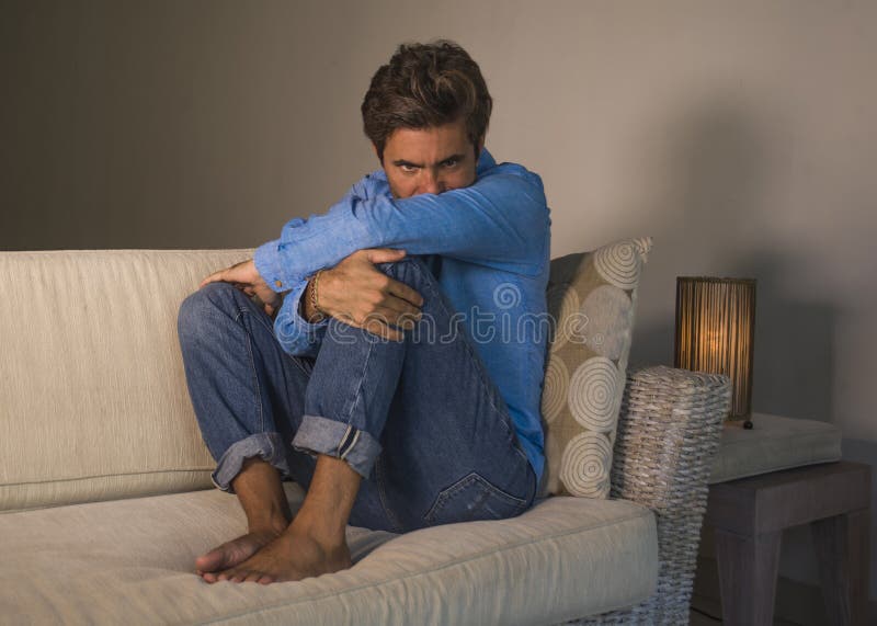 Lifestyle portrait of young attractive and handsome sad latin man sitting tired and depressed at home sofa couch feeling overwhelmed and worried suffering depression crisis and anxiety problem. Lifestyle portrait of young attractive and handsome sad latin man sitting tired and depressed at home sofa couch feeling overwhelmed and worried suffering depression crisis and anxiety problem
