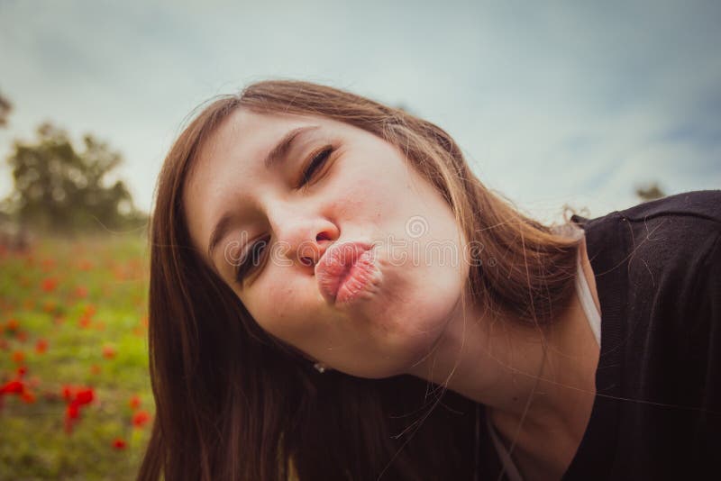 Η νέα παραγωγή γυναικών duckface φιλά παίρνοντας selfie απεικονίζει με το smartphone ή τη κάμερα της στον τομέα των κόκκινων παπα στοκ φωτογραφίες Η νέα παραγωγή γυναικών duckface φιλά παίρνοντας selfie απεικονίζει με το smartphone ή τη κάμερα της στον τομέα των κόκκινων παπα στοκ φωτογραφίες