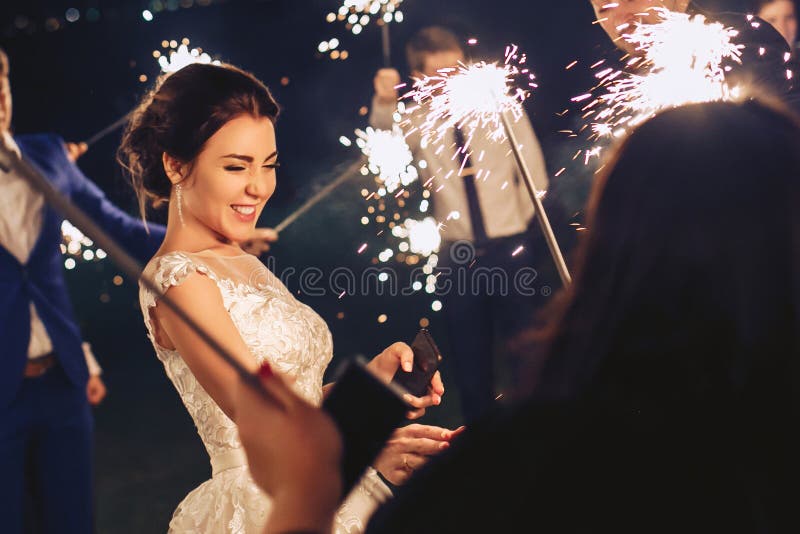 Η νύφη και οι φιλοξενούμενοι κρατούν τα sparklers και διασκεδάζονται στοκ εικόνες