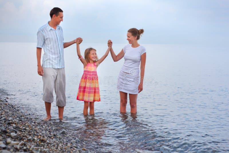 Happy family with little girl walk on beach in evening, having joined hands. Happy family with little girl walk on beach in evening, having joined hands