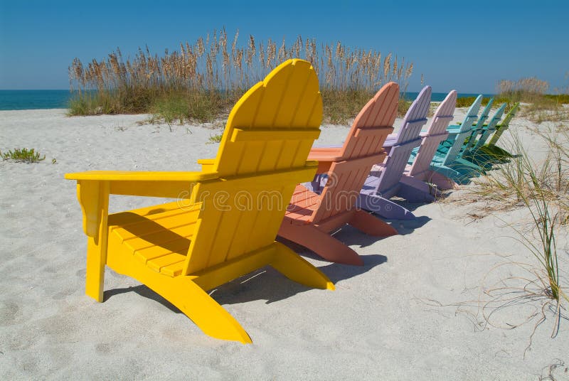 Colorfully painted wooden lawn chairs on a sunny beach. Colorfully painted wooden lawn chairs on a sunny beach.