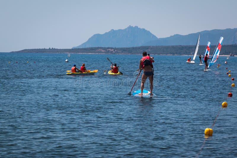 Η στάση επάνω στο άτομο Paddleboarding Surfer εν πλω μεταξύ των κανό και κερδίζει στοκ εικόνες