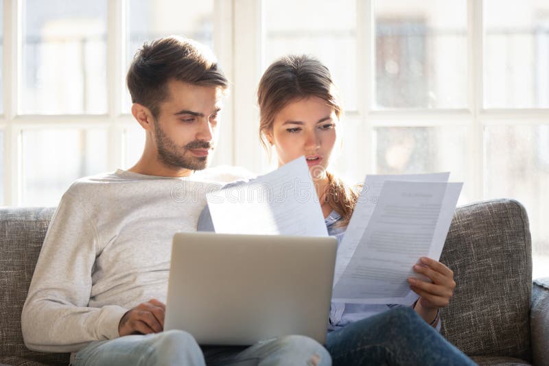 Η συνεδρίαση ζευγών στην ανάγνωση καναπέδων έλαβε την επίσημη επιστολή στοκ εικόνα με δικαίωμα ελεύθερης χρήσης Η συνεδρίαση ζευγών στην ανάγνωση καναπέδων έλαβε την επίσημη επιστολή στοκ εικόνα με δικαίωμα ελεύθερης χρήσης