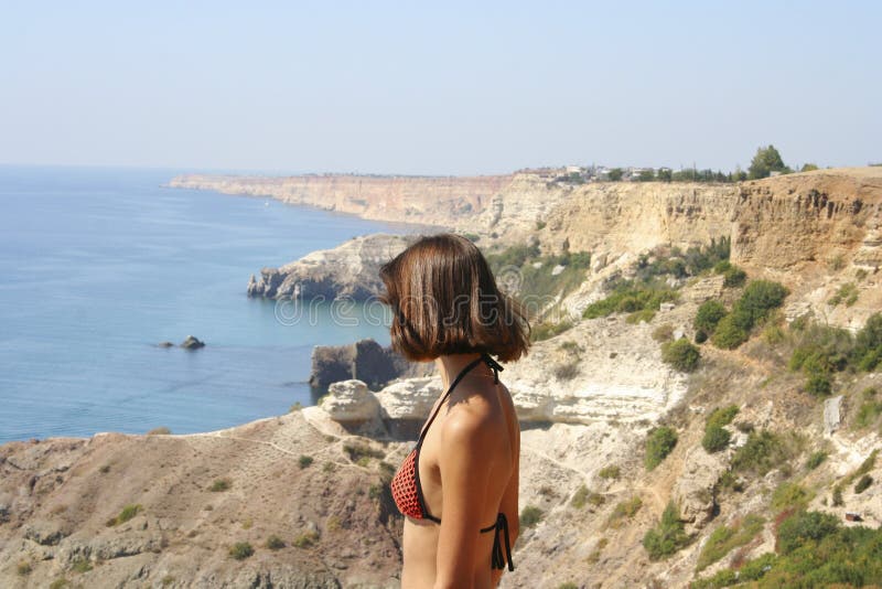 Η όμορφη εικόνα της μπλε θάλασσας με τα βουνά πλησιάζει και νέα στάση γυναικών στοκ φωτογραφία με δικαίωμα ελεύθερης χρήσης Η όμορφη εικόνα της μπλε θάλασσας με τα βουνά πλησιάζει και νέα στάση γυναικών στοκ φωτογραφία με δικαίωμα ελεύθερης χρήσης