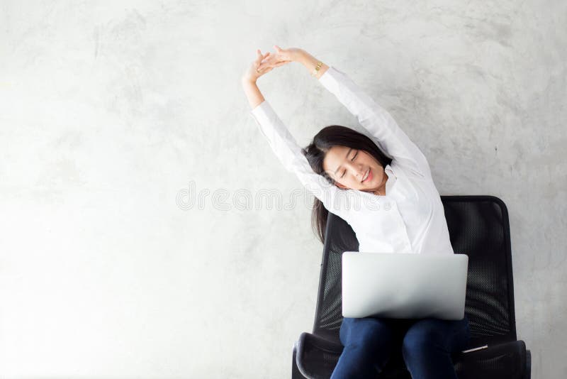 Η όμορφη νέα ασιατική γυναίκα με το τέντωμα lap-top και η άσκηση χαλαρώνουν μετά από την επιτυχία εργασίας στοκ φωτογραφία Η όμορφη νέα ασιατική γυναίκα με το τέντωμα lap-top και η άσκηση χαλαρώνουν μετά από την επιτυχία εργασίας στοκ φωτογραφία