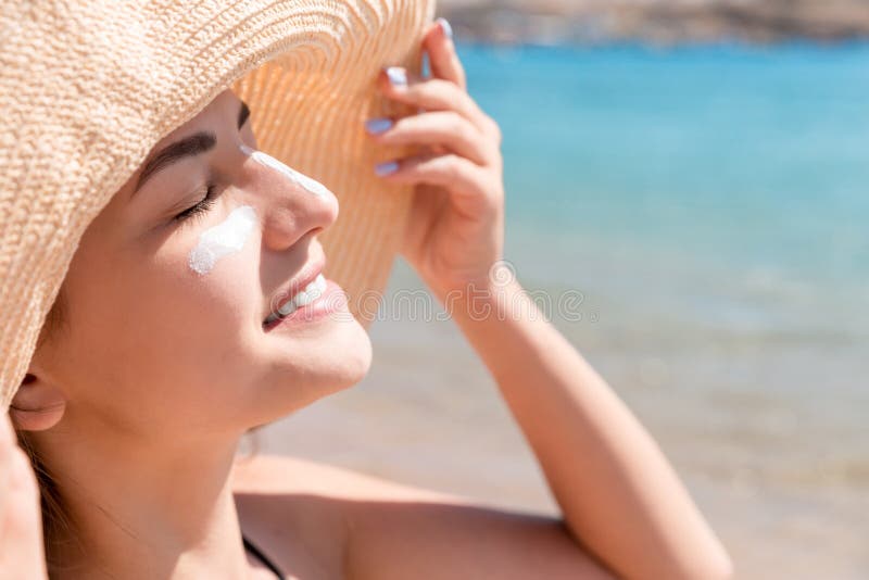 Η όμορφη νέα γυναίκα στο καπέλο ισχύει sunblock κάτω από τα μάτια της και στη μύτη της όπως Ινδό Έννοια προστασίας ήλιων στοκ εικόνες με δικαίωμα ελεύθερης χρήσης Η όμορφη νέα γυναίκα στο καπέλο ισχύει sunblock κάτω από τα μάτια της και στη μύτη της όπως Ινδό Έννοια προστασίας ήλιων στοκ εικόνες με δικαίωμα ελεύθερης χρήσης