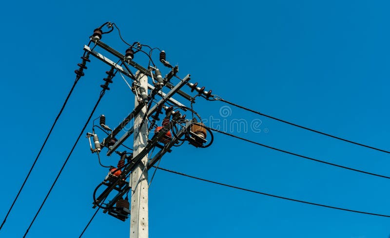 Ηλεκτρικές γραμμές πόλων και μετάδοσης υψηλής τάσης με το σαφή μπλε ουρανό Πυλώνες ηλεκτρικής ενέργειας στο πεδίο κριθαριού Σύστη στοκ εικόνες