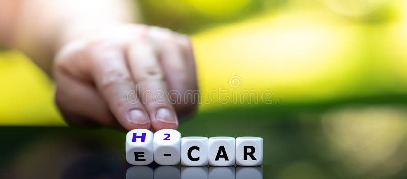 Electric car or a hydrogen car? Hand turns dice and changes the expression `e-car` to `h2 car. Electric car or a hydrogen car? Hand turns dice and changes the expression `e-car` to `h2 car