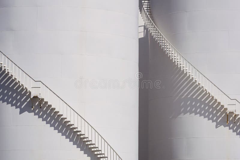 Background of spiral staircases on 2 storage fuel tanks with sunlight and shadow on surface. Background of spiral staircases on 2 storage fuel tanks with sunlight and shadow on surface