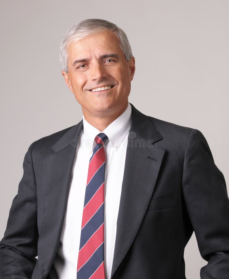 Portrait of a Smiling Middle aged Businessman against a gray background. Portrait of a Smiling Middle aged Businessman against a gray background