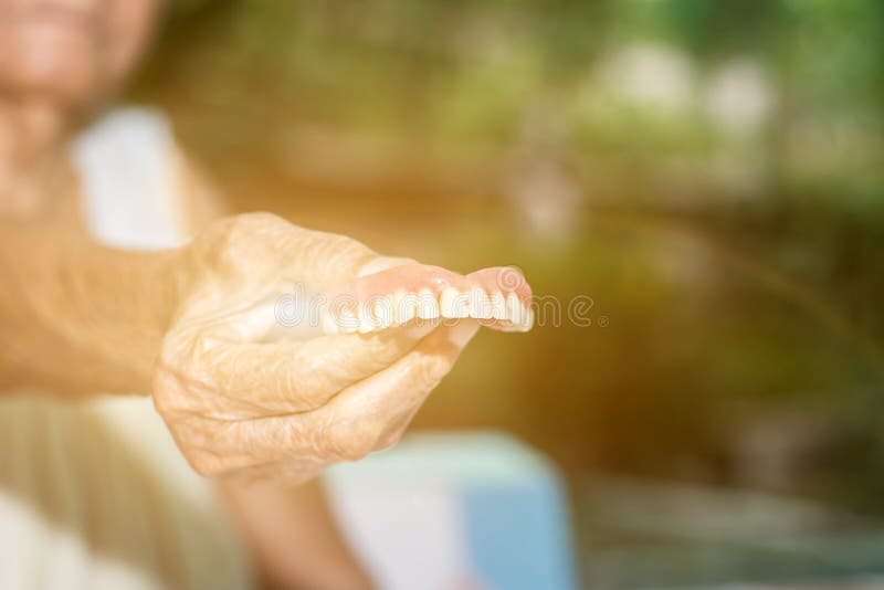 Ηλικιωμένες γυναίκες κρατούν ψεύτικα δόντια με βρώμικα για αποσπώμενο μερικό καθαρισμό με οδοντόβουρτσα στοκ φωτογραφία με δικαίωμα ελεύθερης χρήσης