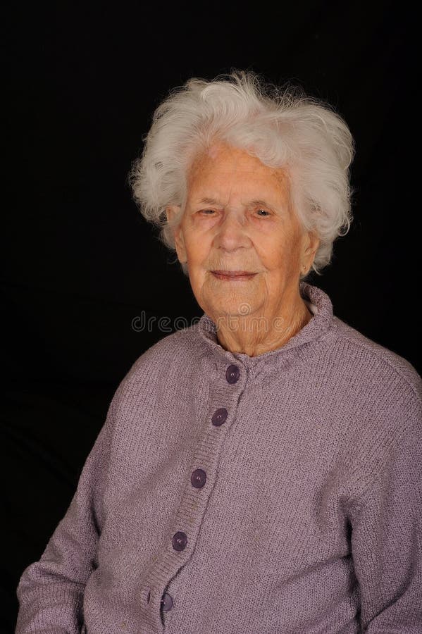 A portrait of a 100 years old woman, on a black studio background. A portrait of a 100 years old woman, on a black studio background.