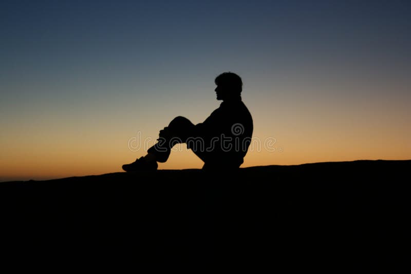 A young man in silhouette at sunset. A young man in silhouette at sunset