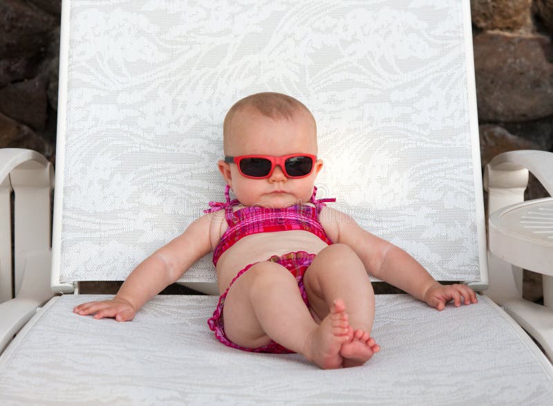 Baby girl with sunglasses smiling in pink bikini sunbathing. Baby girl with sunglasses smiling in pink bikini sunbathing