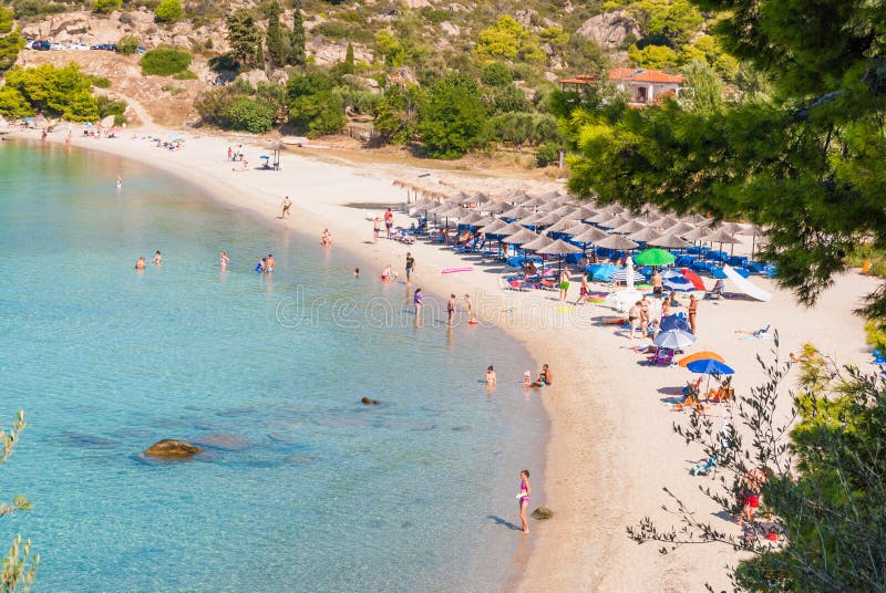 Ηλιόλουστη όμορφη θερινή άποψη της αμμώδους παραλίας με την ελληνική μπλε θάλασσα με το ρηχό καθαρό νερό και τους μικρούς βράχους στοκ φωτογραφία με δικαίωμα ελεύθερης χρήσης Ηλιόλουστη όμορφη θερινή άποψη της αμμώδους παραλίας με την ελληνική μπλε θάλασσα με το ρηχό καθαρό νερό και τους μικρούς βράχους στοκ φωτογραφία με δικαίωμα ελεύθερης χρήσης