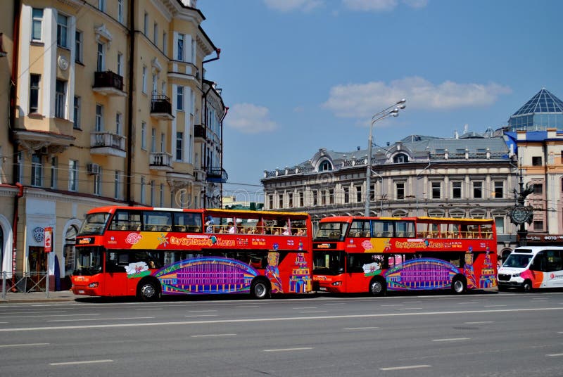 Kazan, Tatarstan, Russia - June 22, 2021: View of tourist red double-decker buses parked on Gabdula Tukay square waiting for tourists on a bright sunny day. Kazan, Tatarstan, Russia - June 22, 2021: View of tourist red double-decker buses parked on Gabdula Tukay square waiting for tourists on a bright sunny day.