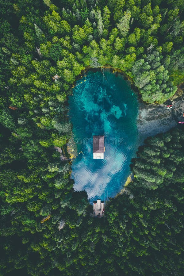 A high angle view of a building in a lake surrounded by forests under a cloudy sky. A high angle view of a building in a lake surrounded by forests under a cloudy sky