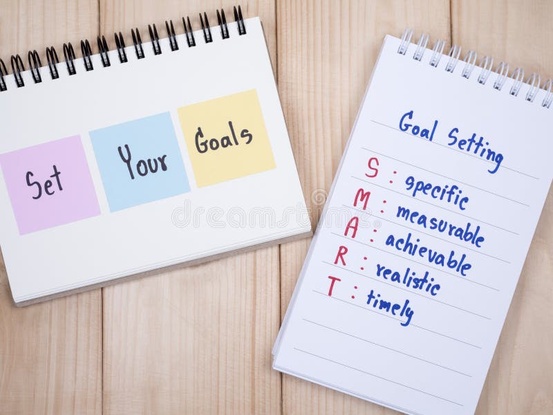 Handwriting Set Your Goals and SMART Goal on notebook with wood background Business Concept. Handwriting Set Your Goals and SMART Goal on notebook with wood background Business Concept