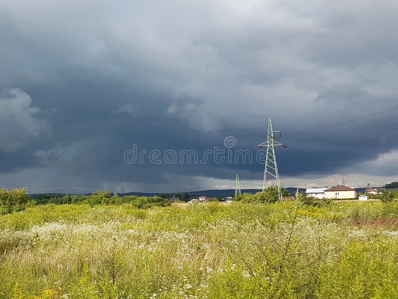 Θερινό λιβάδι στις ακτίνες του ήλιου με μια επικείμενη γραμμή thundercloud και ηλεκτρικής ενέργειας Καιρική αλλαγή Θύελλα μια ηλι στοκ φωτογραφία με δικαίωμα ελεύθερης χρήσης Θερινό λιβάδι στις ακτίνες του ήλιου με μια επικείμενη γραμμή thundercloud και ηλεκτρικής ενέργειας Καιρική αλλαγή Θύελλα μια ηλι στοκ φωτογραφία με δικαίωμα ελεύθερης χρήσης