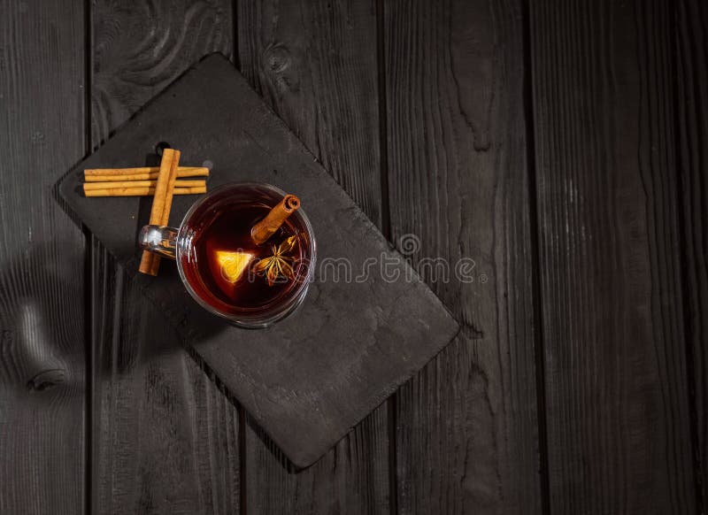 Θερμαμένο κρασί στο μαύρο ξύλινο πίνακα, τα ραβδιά κανέλας και την πορτοκαλιά, τοπ άποψη στοκ φωτογραφία με δικαίωμα ελεύθερης χρήσης Θερμαμένο κρασί στο μαύρο ξύλινο πίνακα, τα ραβδιά κανέλας και την πορτοκαλιά, τοπ άποψη στοκ φωτογραφία με δικαίωμα ελεύθερης χρήσης