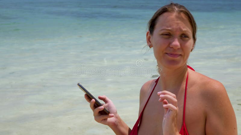θετική όμορφη γυναίκα που χρησιμοποιεί smartphone στην παραλία της θάλασσας απόθεμα βίντεο
