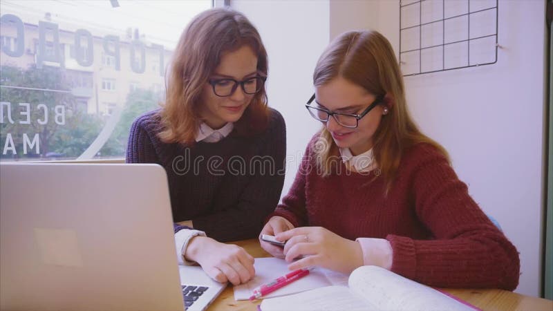 Θηλυκές μελέτες φοιτητών πανεπιστημίου στον καφέ δύο φίλοι κοριτσιών που μαθαίνουν από κοινού