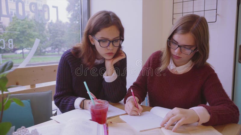 Θηλυκές μελέτες φοιτητών πανεπιστημίου στον καφέ δύο φίλοι κοριτσιών που μαθαίνουν από κοινού