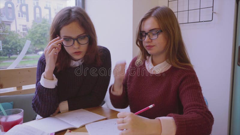 Θηλυκές μελέτες φοιτητών πανεπιστημίου στον καφέ δύο φίλοι κοριτσιών που μαθαίνουν από κοινού