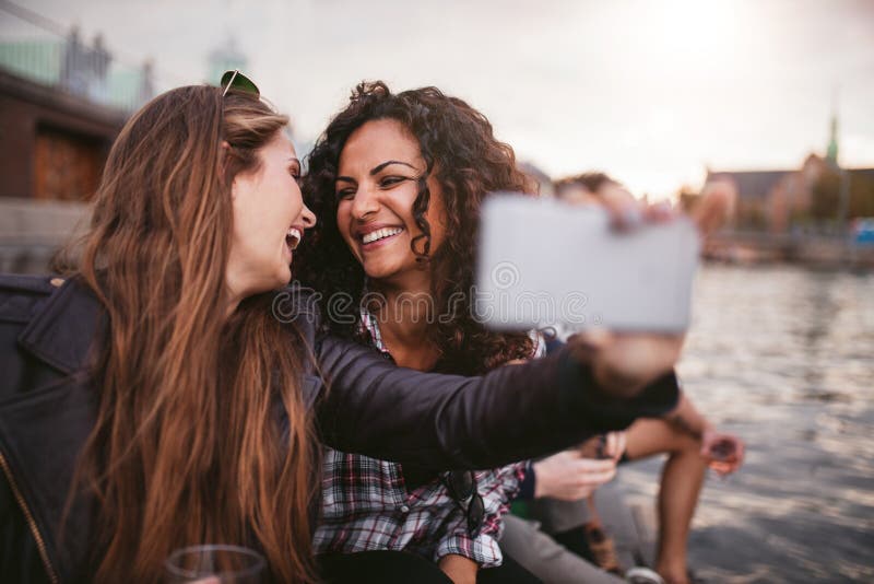 Θηλυκοί φίλοι που παίρνουν selfie από τη λίμνη. Εύθυμοι νέοι φίλοι γυναικών που παίρνουν selfie από τη λίμνη Καλύτεροι φίλοι που έχουν τη διασκέδαση από κοινού