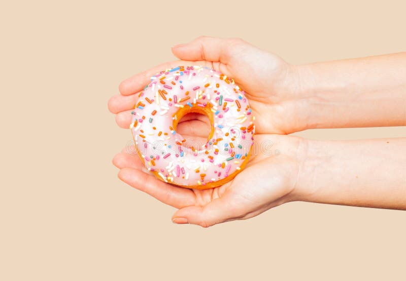 Θηλυκά χέρια που κρατούν ζωηρόχρωμο doughnut στο υπόβαθρο κρητιδογραφιών στοκ εικόνες Θηλυκά χέρια που κρατούν ζωηρόχρωμο doughnut στο υπόβαθρο κρητιδογραφιών στοκ εικόνες