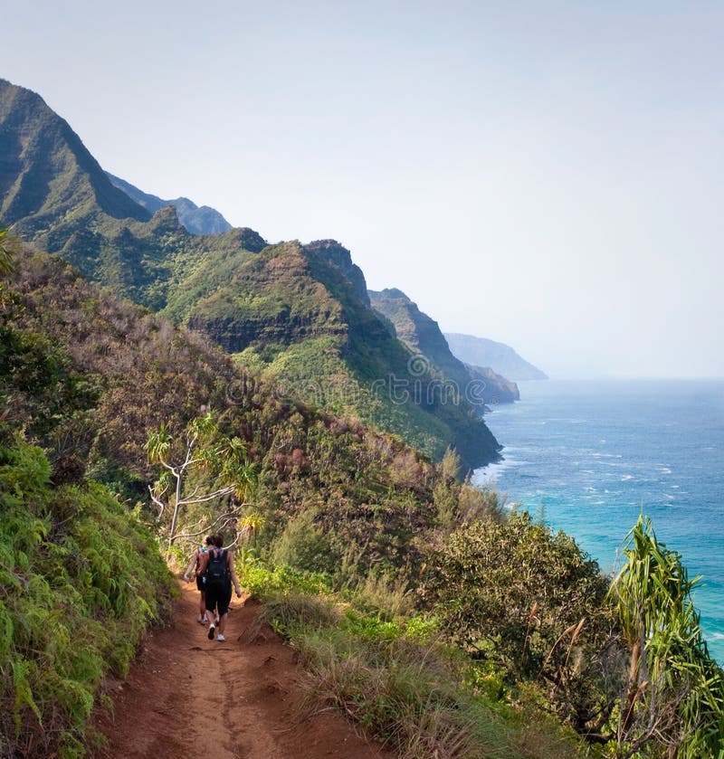 Kalalau trail path on Na Pali coast with three female hikers. Kalalau trail path on Na Pali coast with three female hikers