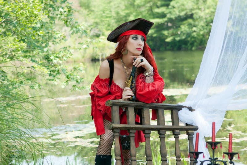Θηλυκό κορίτσι πειρατών με την κόκκινη κορδέλα στη βάρκα με το πιστόλι πειρατών