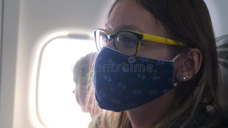 θλιμμένη γυναίκα επιβάτης πτήσης σε σκούρο μπλε πρόσωπο μάσκα πετώ στο αεροπλάνο φιλμ μικρού μήκους