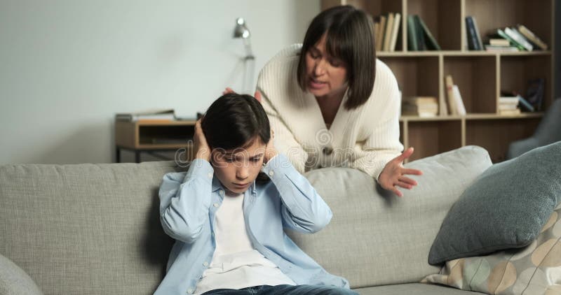 θυμωμένη μητέρα που πνίγει τον γιο όσο κάθεται στον καναπέ