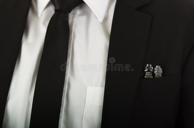 Θωρακική τσέπη σακακιών κοστουμιών κινηματογραφήσεων σε πρώτο πλάνο μαύρη με τα κομμάτια σκακιού γυαλιού που κάθονται μέσα, το άσ στοκ φωτογραφία με δικαίωμα ελεύθερης χρήσης