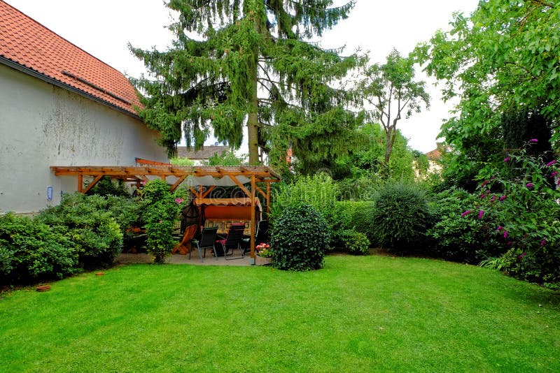 Garden idyll in summer by lush green colors. The backyard with loggia and garden furniture of a German home. Garden idyll in summer by lush green colors. The backyard with loggia and garden furniture of a German home.