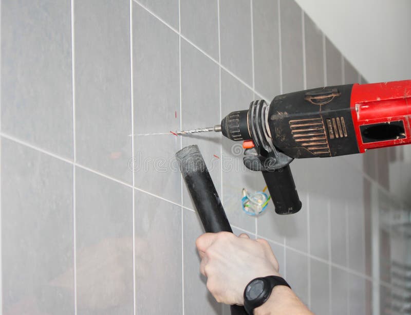 Drilling a marked tile wall to install bathroom fittings. Drilling a marked tile wall to install bathroom fittings