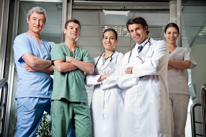 Portrait of confident multiethnic medical professionals standing together with hands folded. Portrait of confident multiethnic medical professionals standing together with hands folded