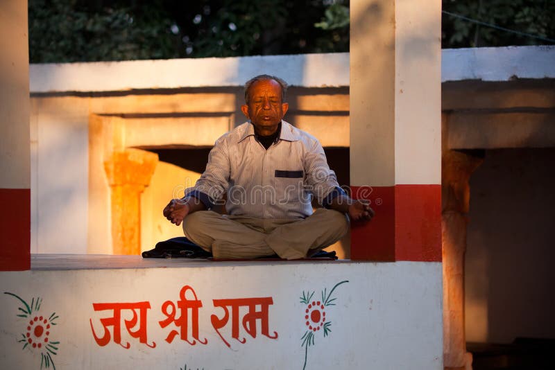 Indian villager old man doing yoga or praying sitting on cemented platform in evening. Indian villager old man doing yoga or praying sitting on cemented platform in evening