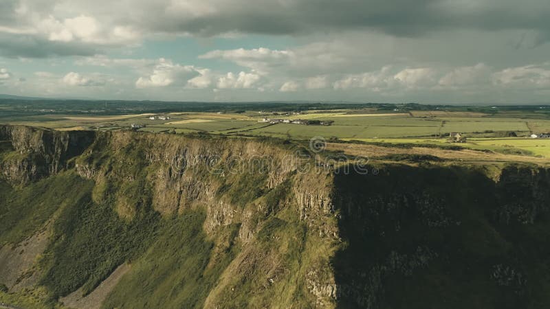 ιρλανδία : τουριστική παραμονή στην κορυφή πράσινου ροκ. άνθρωποι που πεζοπορούν στο γρασίδι στην κορυφή του ωκεανού