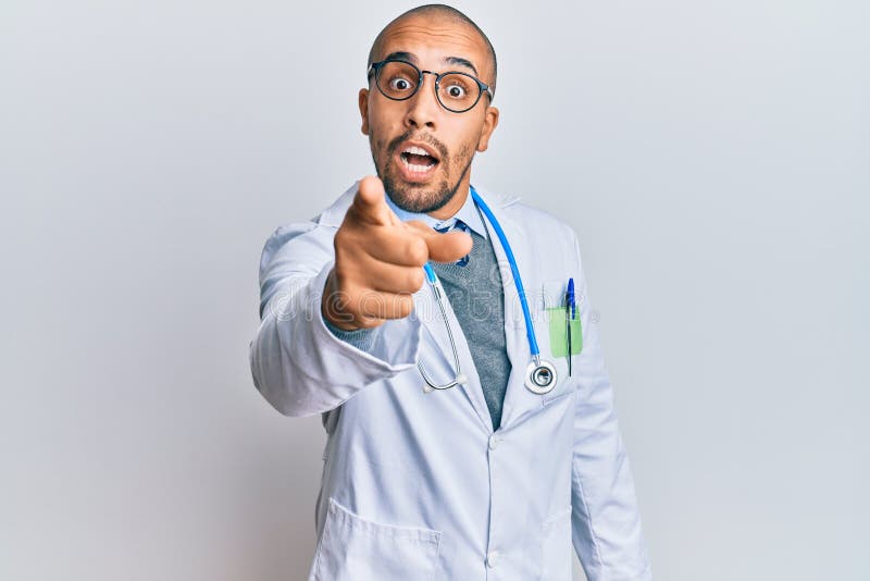 Hispanic adult man wearing doctor uniform and stethoscope pointing displeased and frustrated to the camera, angry and furious with you. Hispanic adult man wearing doctor uniform and stethoscope pointing displeased and frustrated to the camera, angry and furious with you