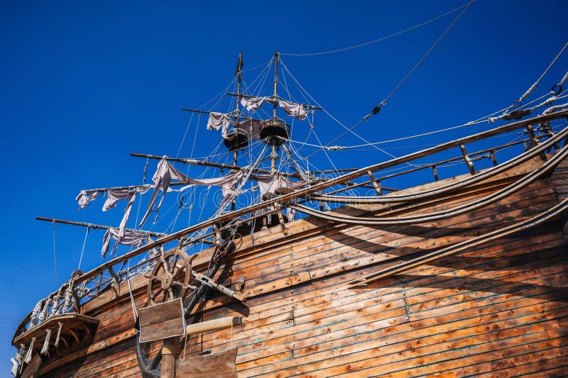 mast with sails on an ancient wooden pirate ship boat on background of blue sky in the sea. mast with sails on an ancient wooden pirate ship boat on background of blue sky in the sea