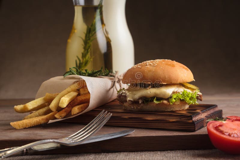 Κλασικό burger με το βόειο κρέας και τις τηγανιτές πατάτες στοκ εικόνα με δικαίωμα ελεύθερης χρήσης